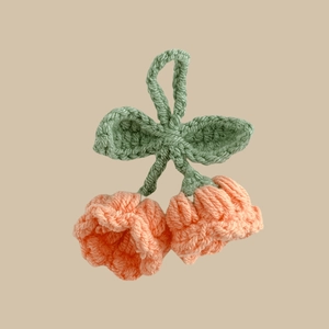 Macro detail of handmade crochet lily of the valley pendant with orange pink petals