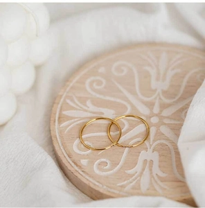 Macro view of minimalist thin gold-plated stainless steel rings on a vintage coaster