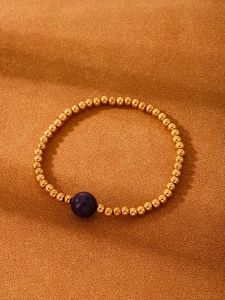 Close-up of 18K gold-plated beaded bracelet with a single purple agate stone detail