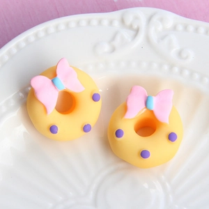 Macro view of 3D yellow donut resin charms with pink bows and purple polka dots