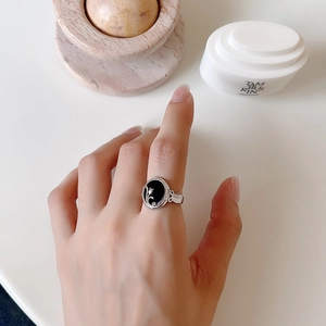 Detail of 925 silver flower ring with black agate stone on hand against white background
