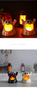 Close-up of glowing Halloween ceramic ghost LED tea lights in black and white finish