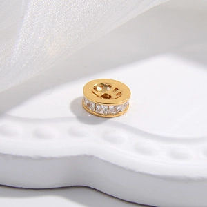 Macro di una perlina distanziatrice dorata con zirconi bianchi per creazione gioielli DIY