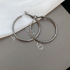 Close-up of silver metal hoop earrings with high gloss finish and needle pin closure