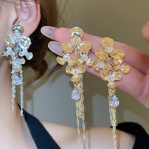Close-up of sparkling flower earrings with long metal tassels and teardrop rhinestones