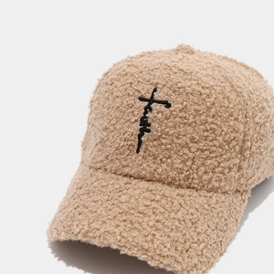 Close-up of beige fleece baseball cap featuring black Faith cross embroidery detail