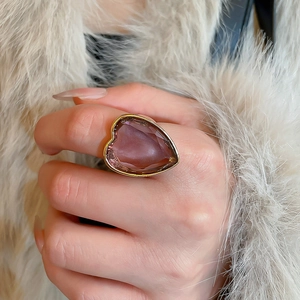 Detail shot of heart-shaped purple gemstone ring with gold plating on a hand