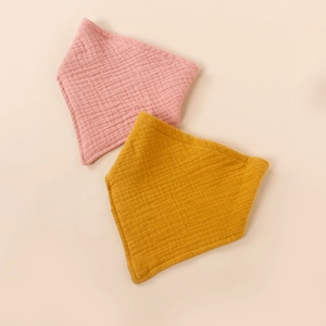Detail of pink and yellow muslin cotton baby bibs with soft wrinkled texture surface