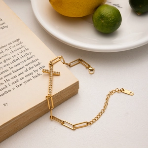 Detailopname van gouden kruisarmband met witte strass op vintage boekpagina's