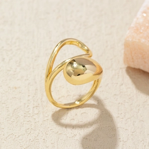 Detailed view of irregular polished gold ring with fluid curved design on a stone base