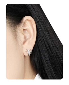 Close-up of minimalist silver bow earrings worn by a model to show fit and size