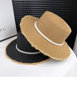 Detail of straw hat with elegant faux pearl band and frayed brim edge finish