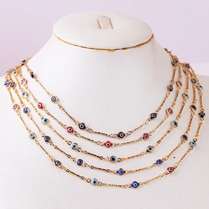 Close-up of layered gold necklace with colorful evil eye charms in blue and red