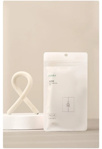 Macro detail of white flexible S-shaped silicone hook with its minimalist packaging