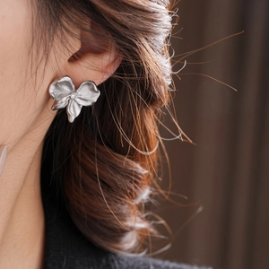 Detailed view of silver pleated flower stud earring with a central sparkling rhinestone