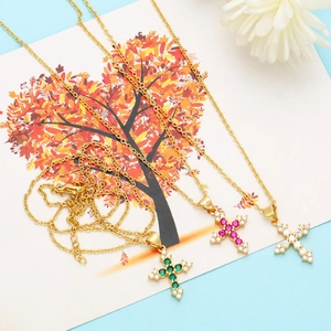 Detailansicht von drei goldenen Kreuzketten mit bunten Zirkonsteinen auf Kunstkarte