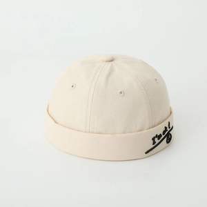 Detail of embroidered smile face and text on beige cotton brimless docker hat