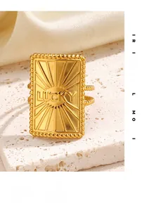 Close-up of golden rectangular LUCKY signet ring with radial texture and beaded band