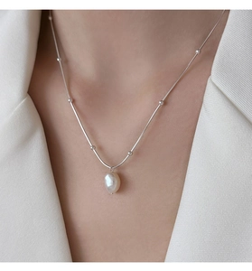 Close-up of a silver stainless steel necklace with a baroque freshwater pearl on a model