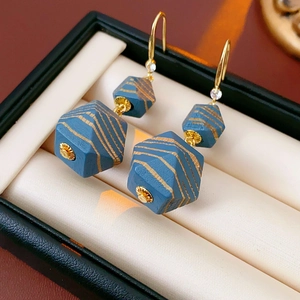 Detail of blue geometric ceramic drop earrings with gold stripes and zircon inlay
