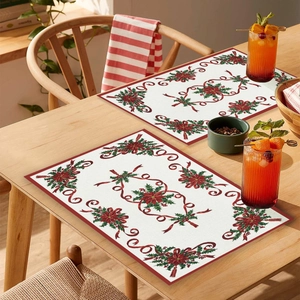 Detail of cream Christmas placemat featuring festive red floral and green holly patterns