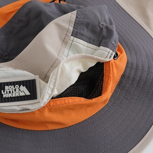 Detail of color-block hiking hat featuring breathable black mesh lining and logo patch