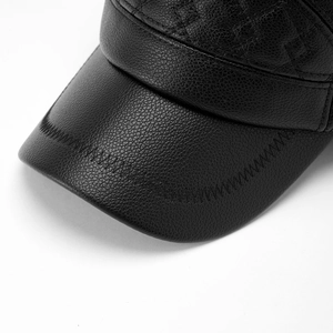 Detailed macro view of black PU leather texture and stitching on the baseball cap brim