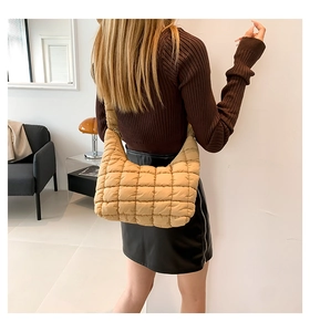 Detail of light beige quilted puffer shoulder bag showing texture and crescent shape on model