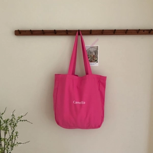 Detailansicht der rosa Canvas-Einkaufstasche mit Camellia-Aufdruck am Holzhaken
