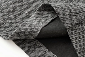 Close-up of grey herringbone tweed fabric and high-quality stitching on short blazer skirt