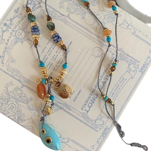 Ethnic style long necklace with turquoise beads and orange stone pendant on a vintage card