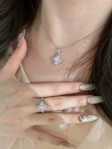 Detailed view of silver necklace and ring set with light purple clover flower petals
