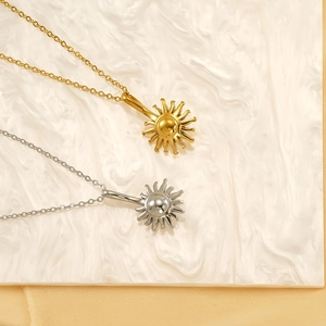 Pendentifs tournesol en acier titane or et argent sur fond de marbre blanc