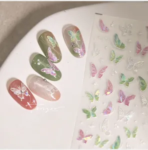 Close-up of 5D butterfly nail stickers with aurora powder finish on a white ceramic plate
