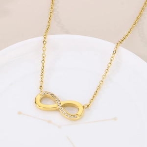 Macro view of gold infinity necklace with pave zircons on a white ceramic tray
