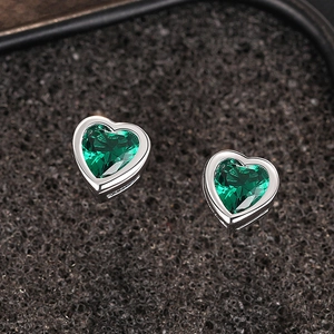 Detailed close-up of heart-shaped emerald green earrings with silver-tone metal claws