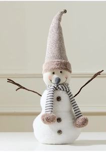 Macro view of plush snowman doll featuring a knit hat, striped scarf, and small bells