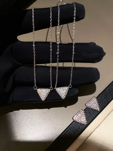Macro shot of silver triangle jewelry set with colorful zircons on a black glove background