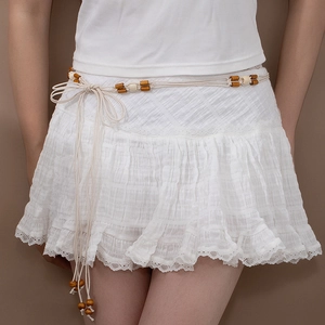 Détail d'une jupe blanche bohème avec bordure en dentelle et ceinture à glands