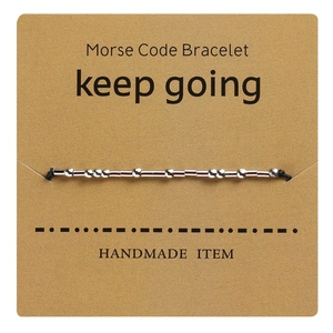 Detail of Morse code bracelet with keep going text on a brown handmade craft card