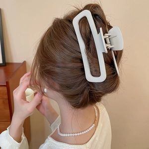 Dettaglio della pinza per capelli cava beige opaco su un'elegante acconciatura raccolta