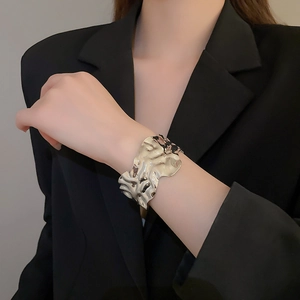 Macro detail of high-shine wide textured metal bracelet with liquid pleated surface on wrist