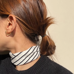 Close-up of a model wearing golden C-shaped oval stud earrings with a silk scarf