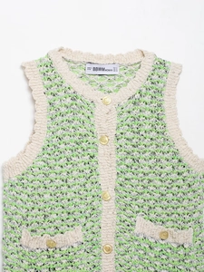 Detail of green and white textured knit vest with embossed gold buttons and brand label