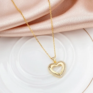 Elegant gold heart pendant necklace with shimmering zircons on pink silk background