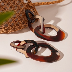 Detail of interlocking amber resin geometric earrings with a tortoise shell texture
