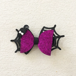 Detail of Halloween bow hair clip featuring purple glitter spider web and a black spider