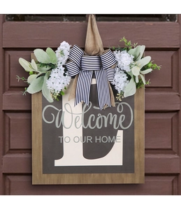 Macro detail of wooden door sign with L letter, white flowers and striped bow decoration