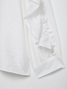 Détail de la manche de chemisier blanc avec poignets à volants délicats et texture de tissu