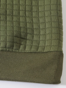 Detailed close-up of army green waffle knit fabric and ribbed hem on men sweatshirt